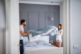 Person making the bed as part of simple daily cleaning habits to maintain a clean home